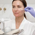 Patient receiving CO2 laser facial aftercare as clinician applies ointment; mild redness and healing skin visible